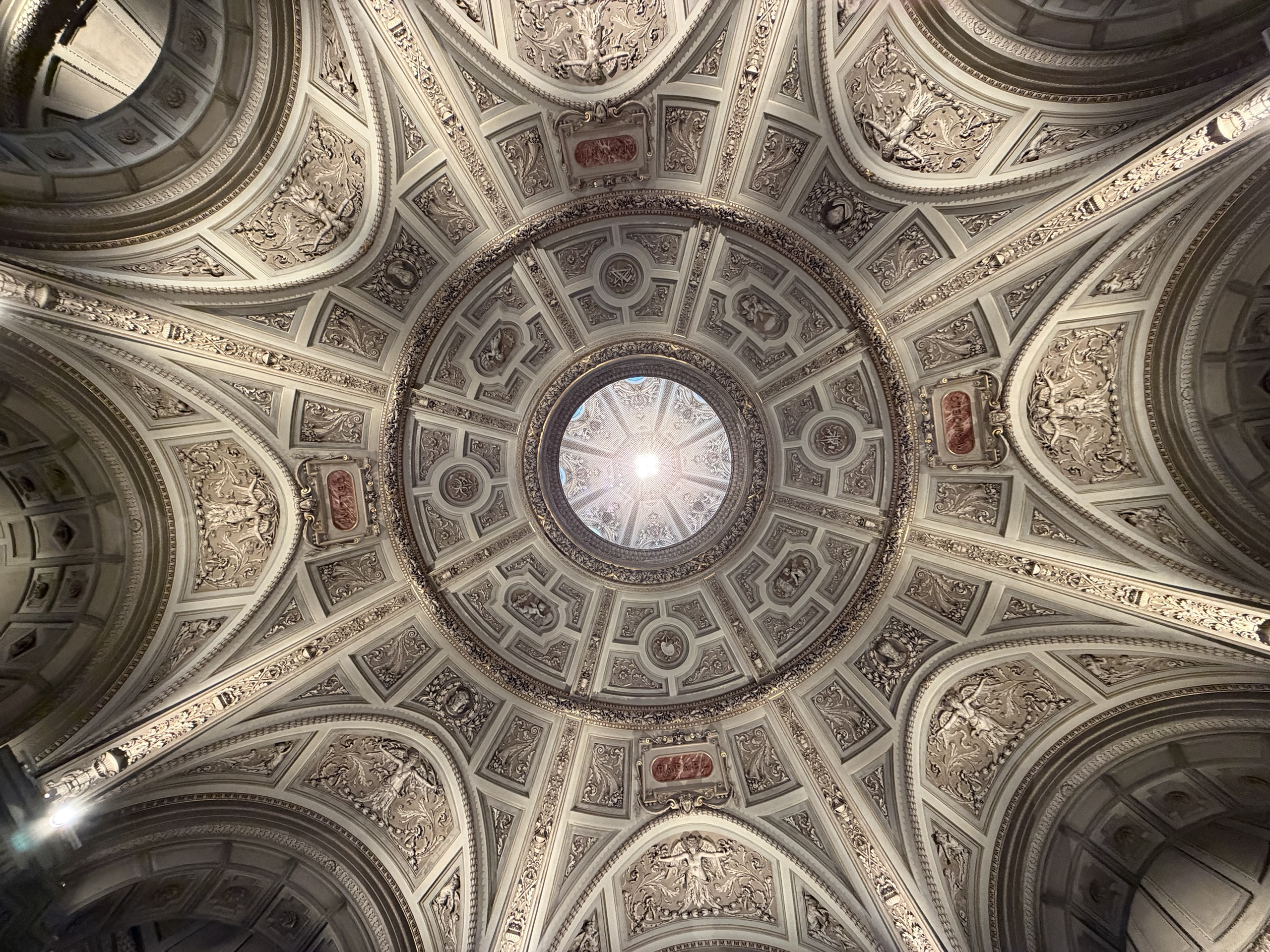 An ornate domed ceiling with carved panels and a circular skylight.