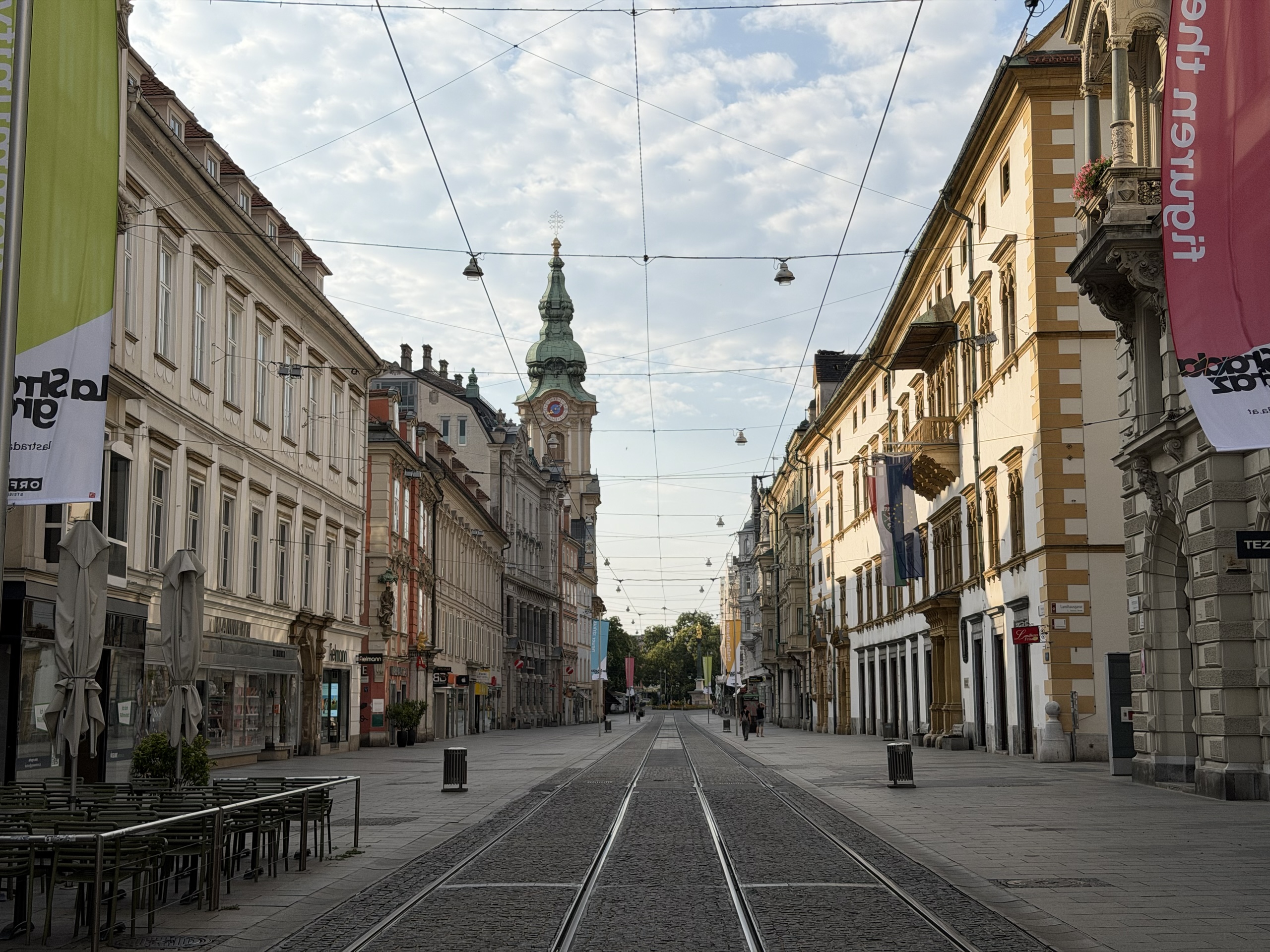 Tram tracks run along a quiet street lined with historic buildings and overhead wires.