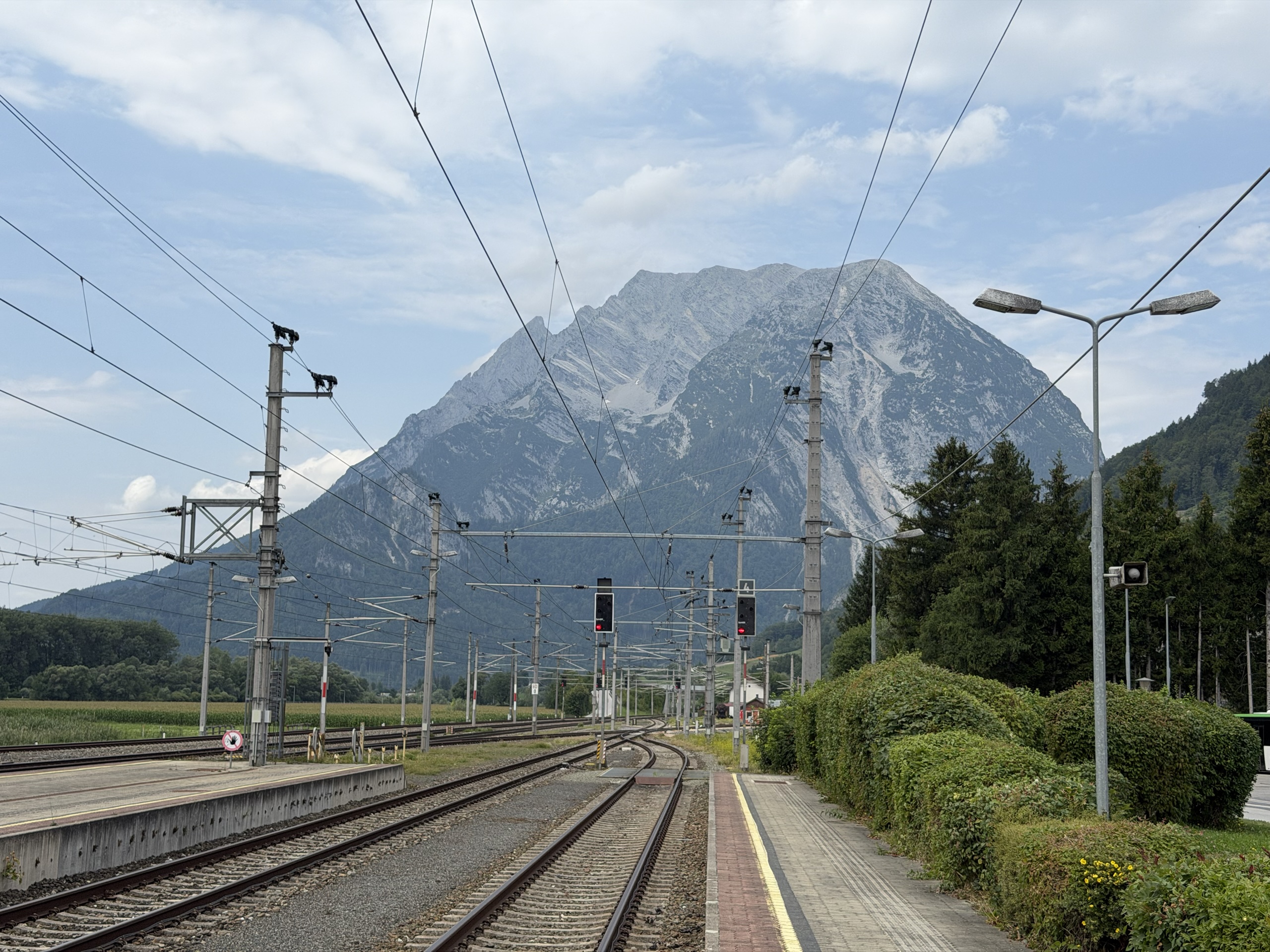 Railway tracks and overhead power lines lead toward a large mountain.